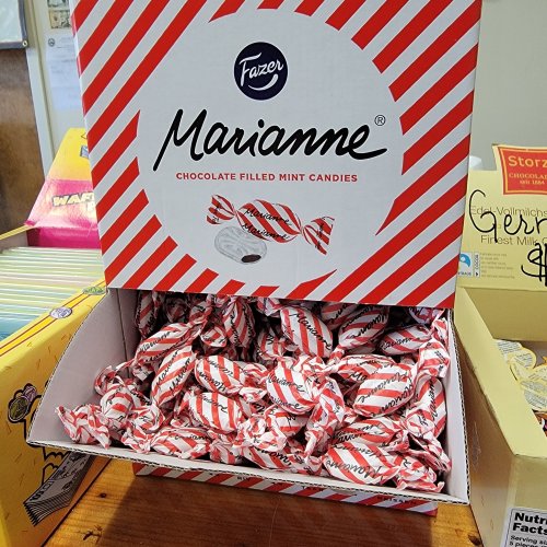 A box of Fazer Marianne chocolate-filled mint candies, featuring red and white striped packaging, filled with individually wrapped candies.