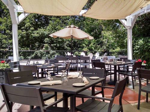 Outdoor dining area with tables, chairs, and an umbrella, surrounded by greenery and a relaxed atmosphere.