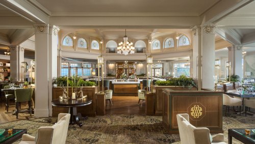 Elegant restaurant interior featuring large windows, chandeliers, and a mix of seating arrangements.