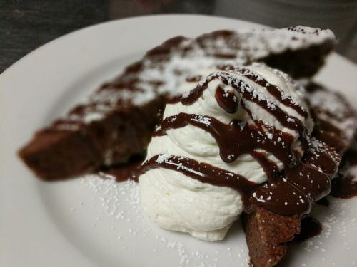 A plate with chocolate cake slices topped with whipped cream and drizzled with chocolate sauce.