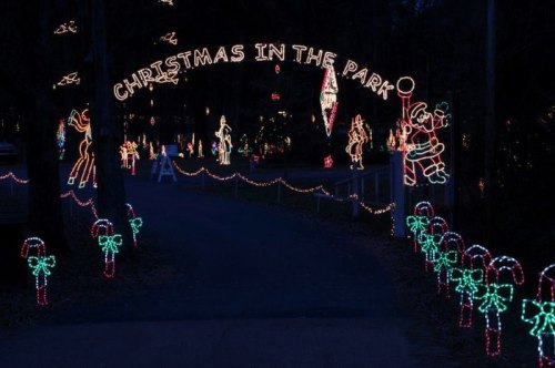 A festive display of Christmas lights in a park, featuring decorations like Santa, candy canes, and holiday figures.