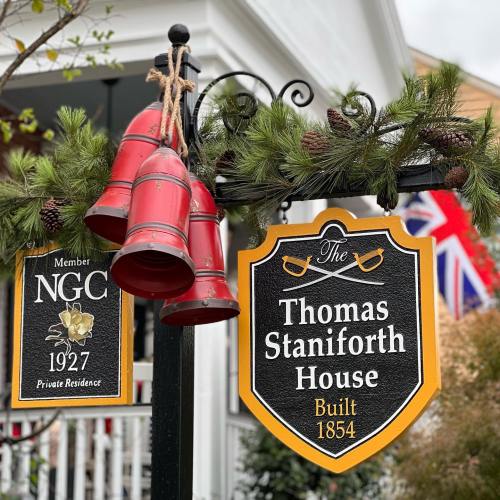 Sign for the Thomas Staniforth House, built in 1854, with decorative bells and greenery. Private residence.