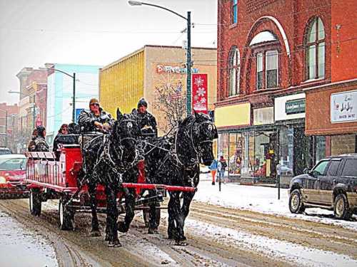 A horse-drawn sleigh carries passengers through a snowy street, with shops and buildings in the background.