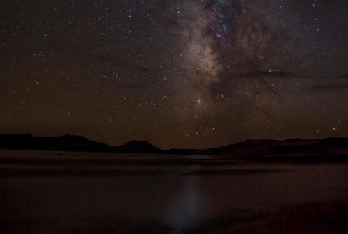 A starry night sky filled with the Milky Way over a dark, tranquil landscape.