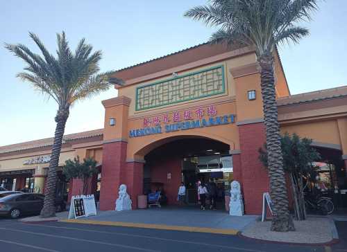 Entrance of Mekong Supermarket with palm trees and decorative architecture. Shoppers are entering the store.