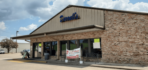 A brick building with a sign reading "Donell's," featuring large windows and signs advertising takeout orders.