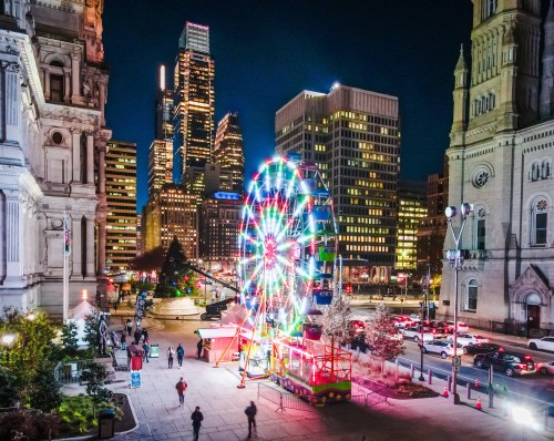 A vibrant cityscape at night featuring a colorful ferris wheel, skyscrapers, and bustling streets.