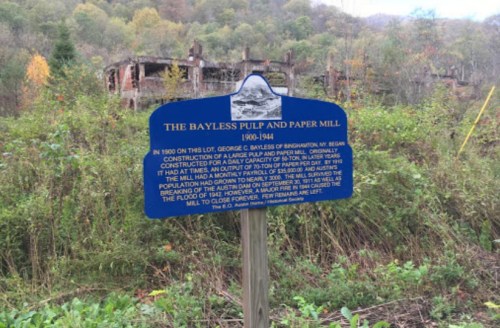Sign about the Bayless Pulp and Paper Mill, detailing its history from 1904 to 1984, with ruins visible in the background.