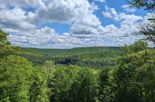 A scenic view of lush green hills under a partly cloudy blue sky.