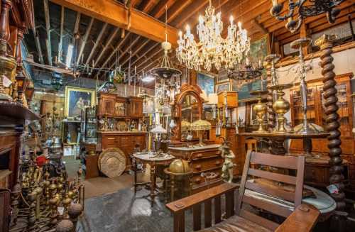 A cozy antique shop filled with vintage furniture, chandeliers, and various decorative items. Warm, inviting atmosphere.