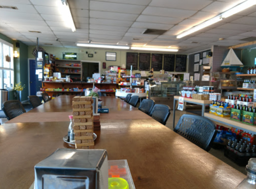A spacious, well-lit store interior with wooden tables, shelves of products, and a game tower in the center.