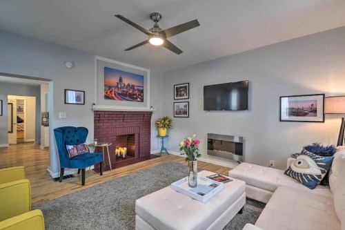 Cozy living room with a fireplace, modern furniture, and colorful decor, featuring a blue chair and wall art.