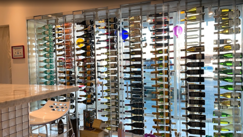 A wall of colorful wine bottles displayed in a modern setting, with a bar counter in the foreground.