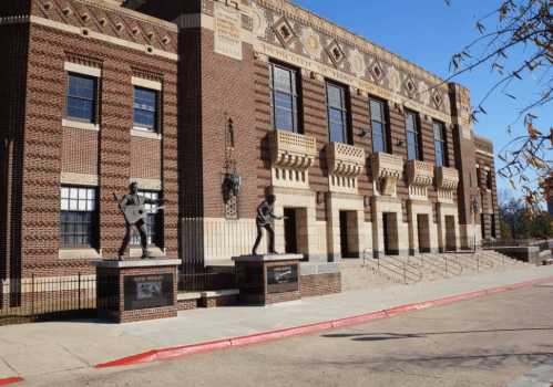 Historic building with brick facade, featuring statues of musicians at the entrance and clear blue sky above.