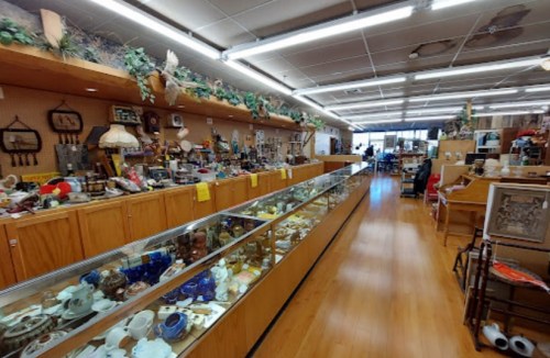 A spacious antique shop filled with various collectibles and displays along wooden counters and shelves.