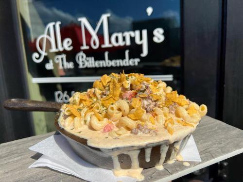 A creamy pasta dish topped with crispy bits, served in a small skillet, with a restaurant sign in the background.