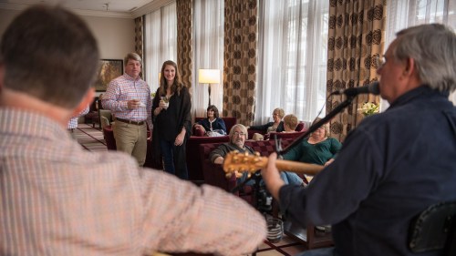 A cozy gathering with people enjoying live music, drinks, and conversation in a warmly lit lounge setting.