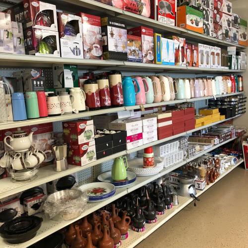 A display of various kitchenware, including kettles, cookware, and utensils, organized on shelves in a store.