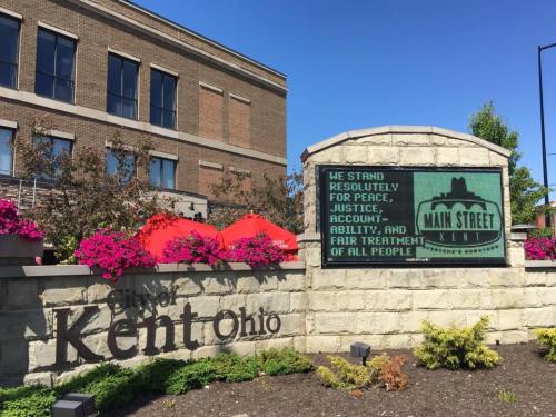 Sign in Kent, Ohio, displaying a message about peace, justice, accountability, and fair treatment, surrounded by flowers.