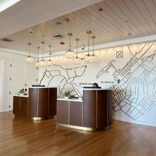 Modern hotel reception area with elegant lighting and a decorative wall map. Warm wood flooring complements the design.