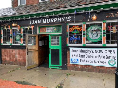 Exterior of Juan Murphy's pub with a welcoming entrance and a sign indicating it's open for dine-in and patio seating.