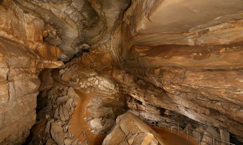 A rocky cave interior with winding paths and natural formations, illuminated by soft light.