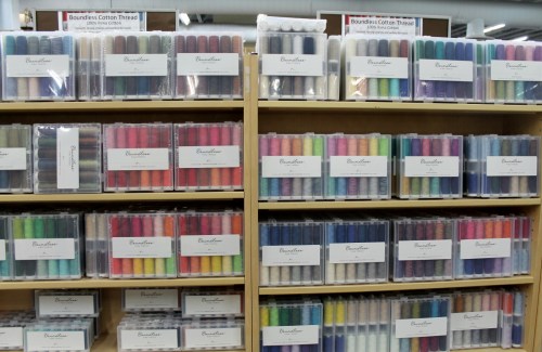 Shelves filled with colorful spools of Boundless Cotton Thread, neatly organized in clear packaging.