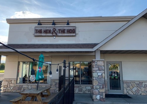 Exterior of a restaurant named "The Hen & The Hog," featuring a stone facade and outdoor seating area.