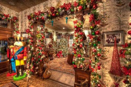 A festive room adorned with Christmas decorations, including a nutcracker, garlands, and multiple decorated trees.