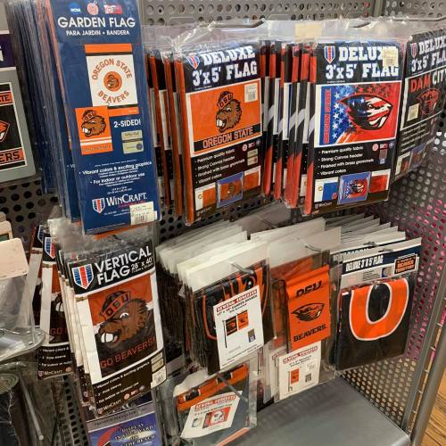 Display of various Oregon State Beavers flags, including garden, deluxe, and vertical flags, on a store shelf.