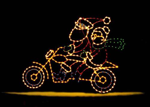 A festive light display featuring Santa and a snowman riding a motorcycle.