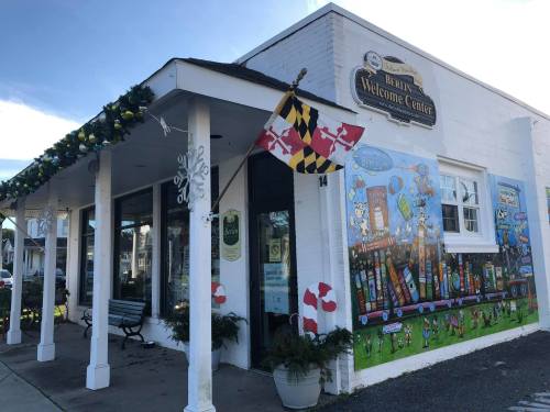 A charming welcome center with festive decorations and a colorful mural on the side, set against a clear blue sky.
