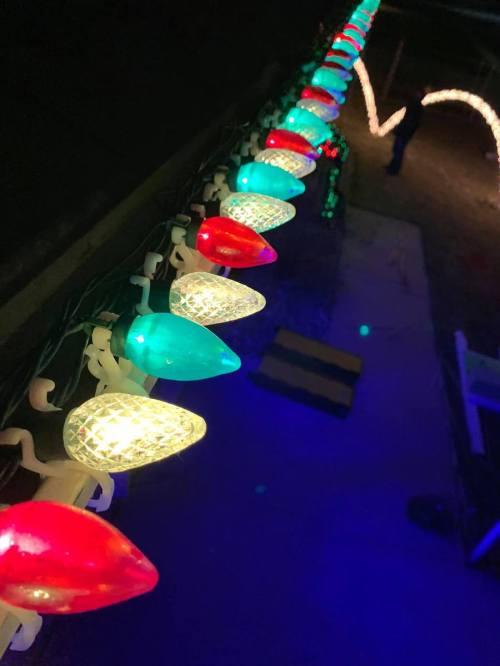 Colorful holiday lights in red, green, and blue arranged along a dark surface, creating a festive atmosphere.