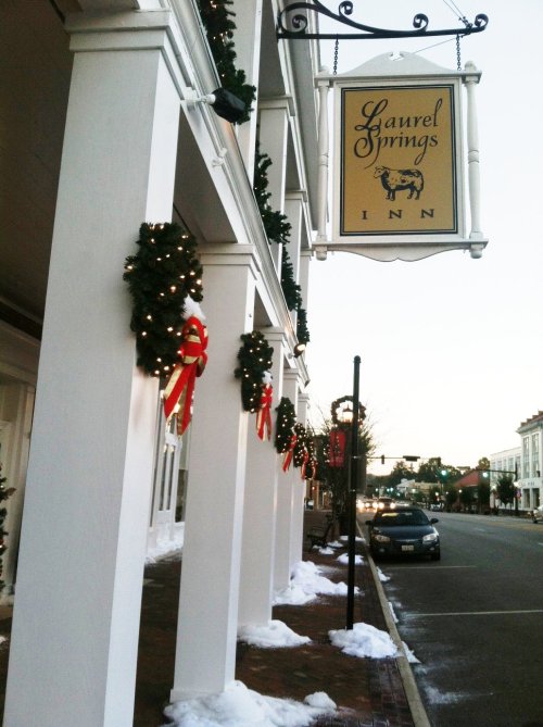 A festive inn decorated with wreaths and ribbons, with snow on the ground and a sign reading "Laurel Springs Inn."