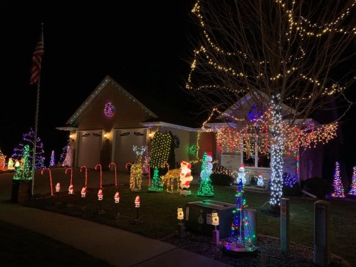 A brightly lit house decorated with colorful Christmas lights, candy canes, and festive figures in a nighttime setting.