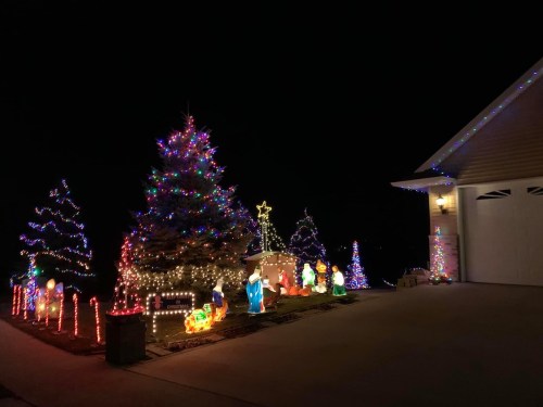 A festive display of colorful Christmas lights and decorations, featuring a large tree and various illuminated figures.