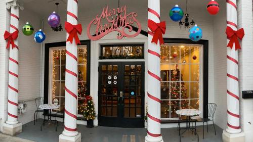 Festive storefront decorated for Christmas with a "Merry Christmas" sign, ornaments, and holiday lights.