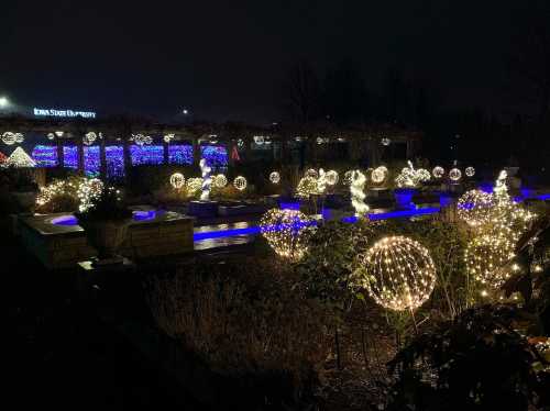 A nighttime view of a garden decorated with glowing spherical lights and colorful displays at a university.