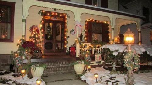 A beautifully decorated house with holiday lights and snow-covered steps, creating a festive winter scene.