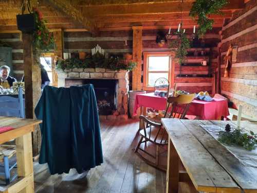 Cozy log cabin interior with a fireplace, wooden furniture, and festive decorations, creating a warm atmosphere.