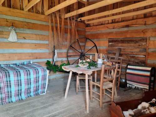 A rustic interior featuring a wooden table, chairs, a plaid blanket, and traditional decor in a cozy, warm setting.