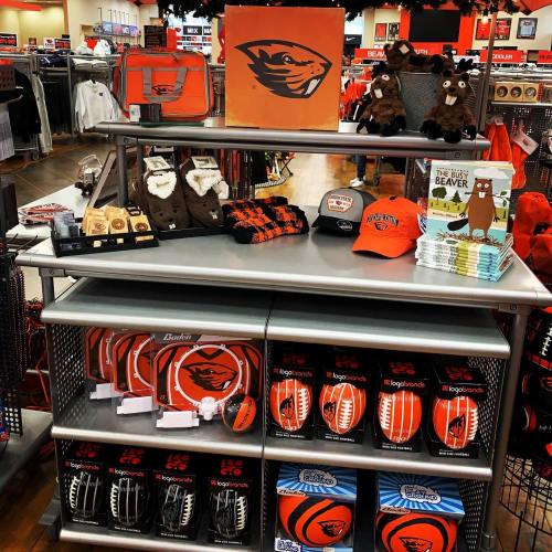 Merchandise display featuring Oregon State University items, including hats, plush toys, and sports gear.