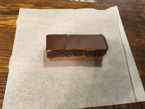 A rectangular chocolate dessert bar on a piece of parchment paper, resting on a wooden surface.