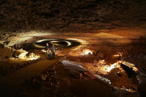 A group of people exploring a dimly lit cave with illuminated rock formations and winding paths.
