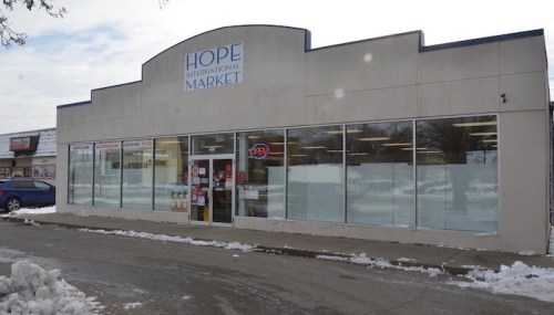 Exterior of Hope International Market, featuring large windows and an "OPEN" sign, with snow on the ground.