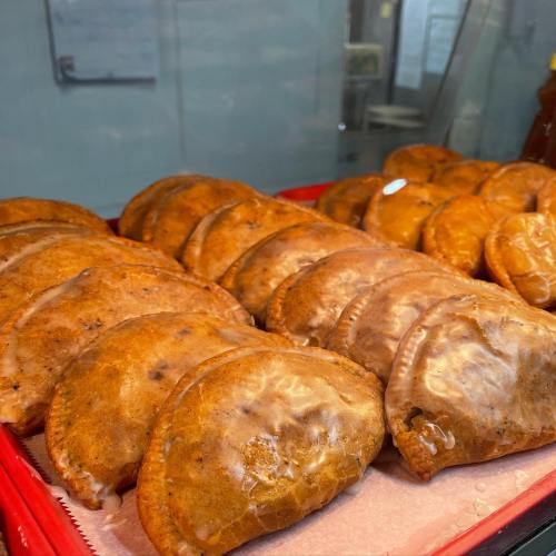 A tray of golden-brown pastries with a glossy glaze, arranged neatly in a display case.