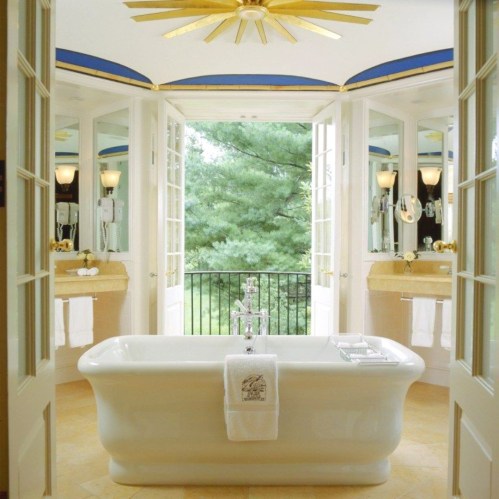 Bright bathroom with a freestanding tub, large windows, and elegant decor overlooking a green landscape.