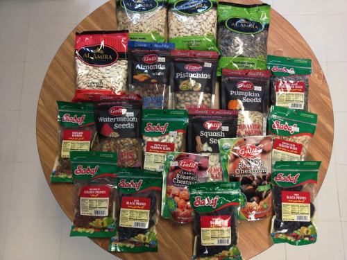 A variety of packaged nuts and seeds displayed on a round wooden table.