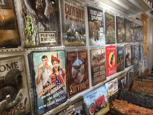 A wall display featuring various vintage-style posters and signs with outdoor and hunting themes.
