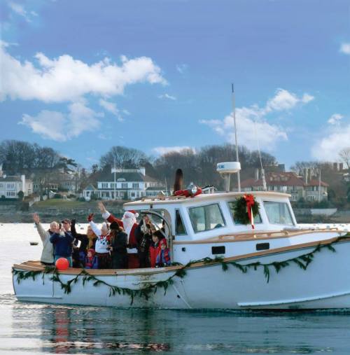 A festive boat decorated for the holidays, with people in Christmas attire waving joyfully from the deck.